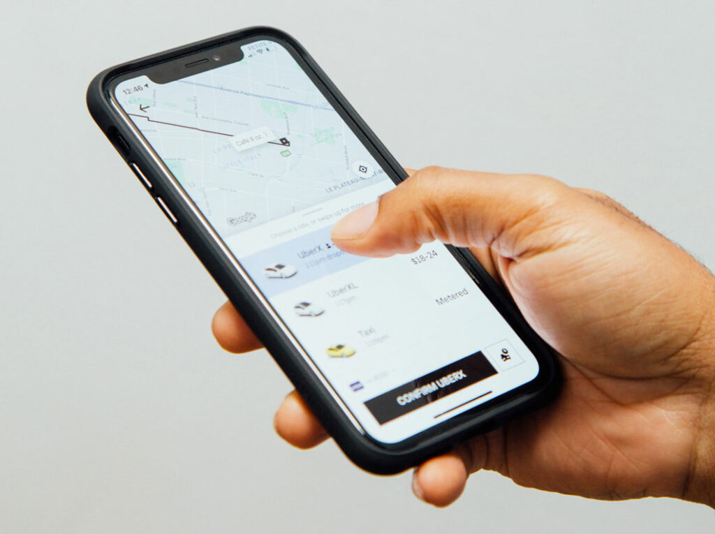 Hand holding cell phone with uber ride sharing service on the screen.