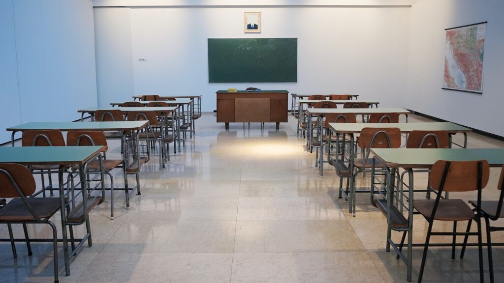 An empty classroom functions as a metaphor for Colombian education. By Ivan Aleksic on Unsplash.